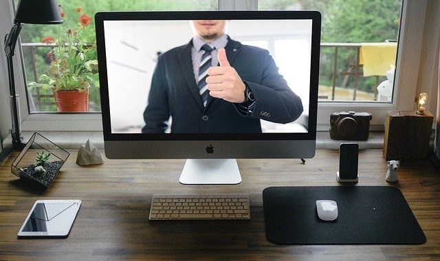 computador sobre uma mesa com imagem de um homem de terno, algo como parte de uma audiência virtual na prática