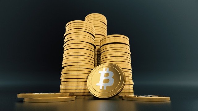 pilha de moedas e uma com a logomarca do bitcoin